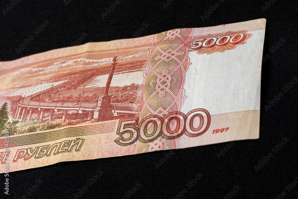 One Russian bill in the amount of 5000 rubles lies on the back on a black background. One Russian bill in the amount of 5000 rubles lies on the back on a black background.