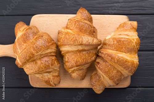 Croissants on a black wooden table. Croissant breakfast. Croissants on a wooden board and a black wooden table. Fresh French Baked Croissants. Warm Fresh Buttery Rolls. Free space for text. View from 