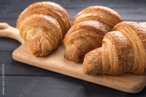 Croissants on a black wooden table. Croissant breakfast. Croissants on a wooden board and a black wooden table. Fresh French Baked Croissants. Warm Fresh Buttery Rolls. Free space for text.