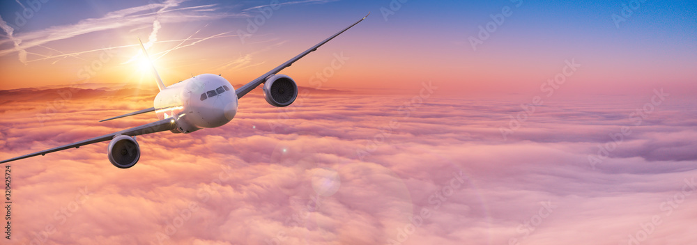 Fototapeta Commercial airplane jetliner flying above dramatic clouds in beautiful sunset light. Travel concept.