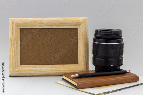 Composition Using Empty Frame, Printed Photos, Camera Lens, Notebook and Black Pencil on Gray Background