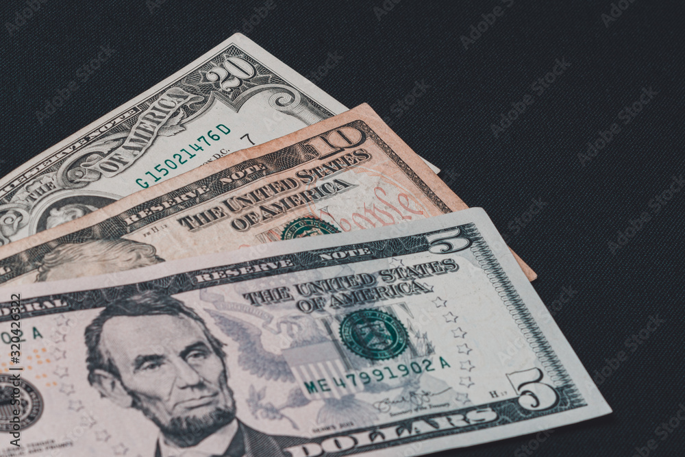 Five, ten and twenty dollar bills lie on a black background. Five, ten and twenty dollar bills lie on a black background.