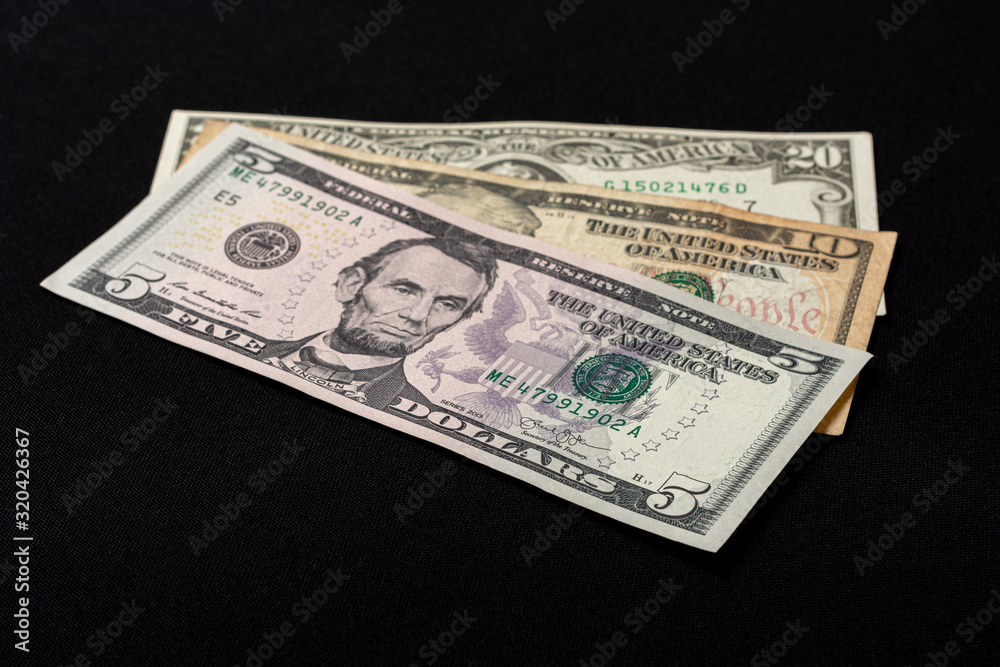 Five, ten and twenty dollar bills lie on a black background. Five, ten and twenty dollar bills lie on a black background.