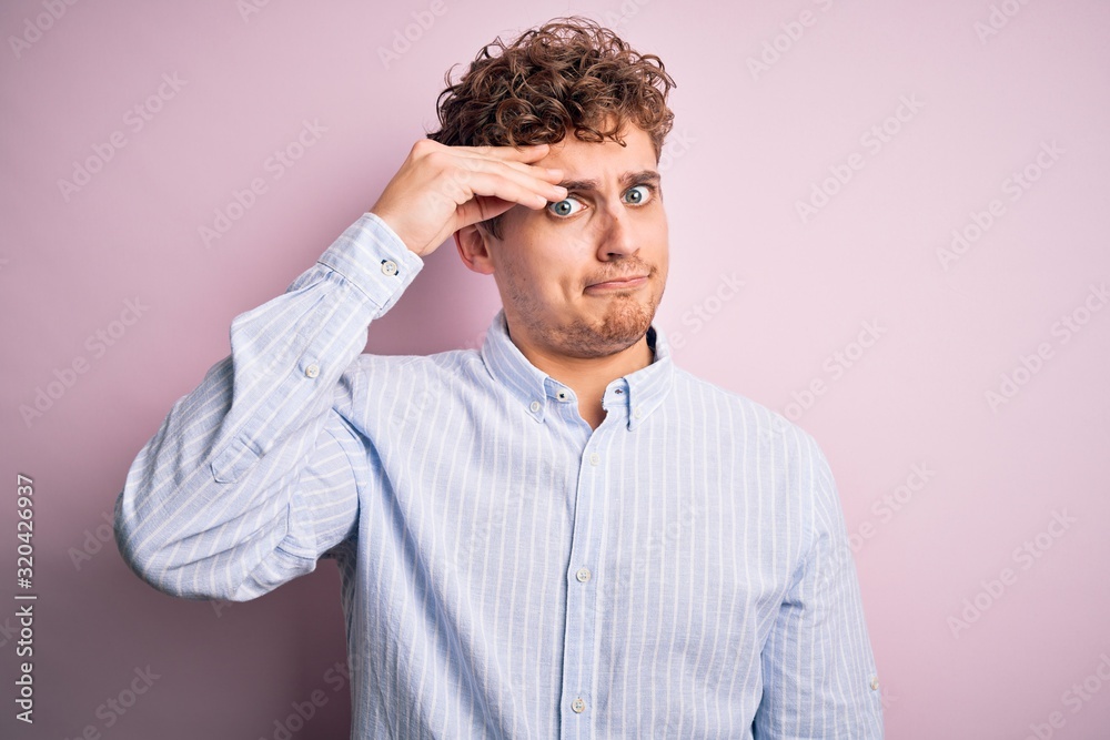 Young blond handsome man with curly hair wearing striped shirt over white background worried and stressed about a problem with hand on forehead, nervous and anxious for crisis Young blond handsome man with curly hair wearing striped shirt over white background worried and stressed about a problem with hand on forehead, nervous and anxious for crisis