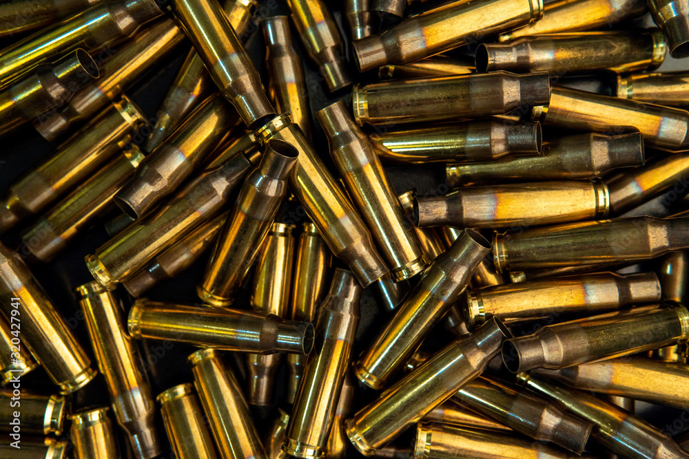Background from empty cartridges for rifles and carbines. Shiny brass shells scattered on the surface.