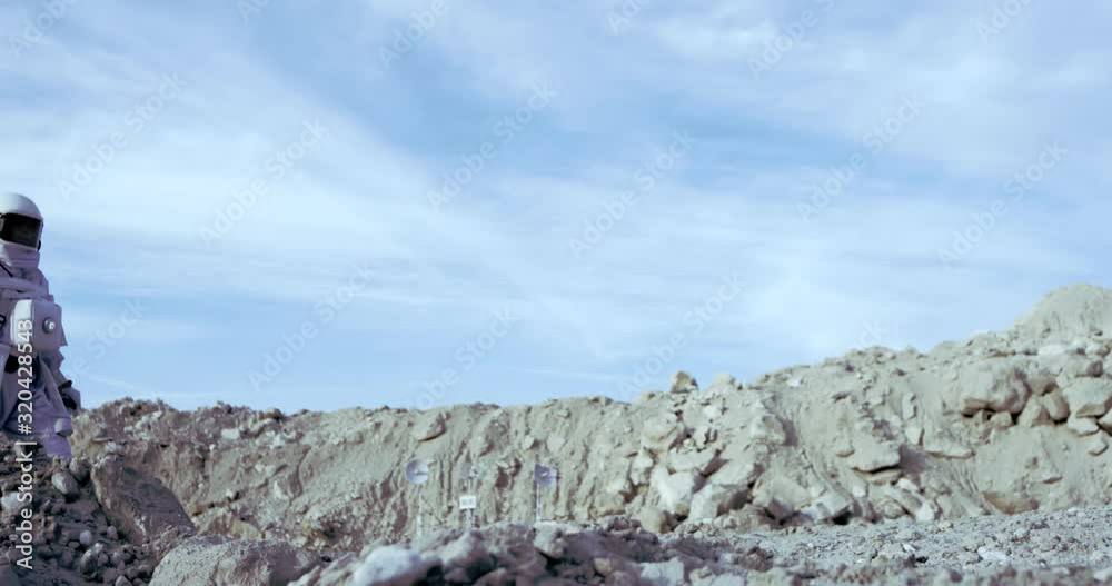 NASA female cosmonaut stepping on the stoned ground of the uninhabited palnet, then stopping and looking around. Outdoors. NASA female cosmonaut stepping on the stoned ground of the uninhabited palnet, then stopping and looking around. Outdoors.