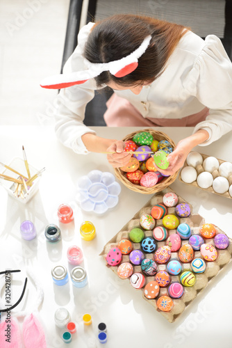 Easter, holiday concept - top view of young women coloring eggs for easter