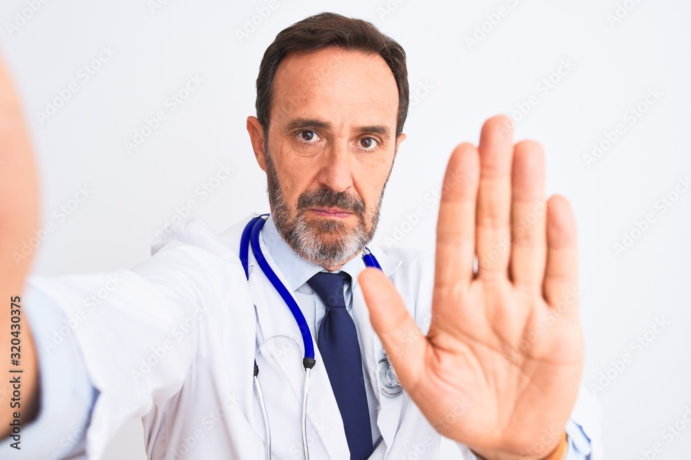 Middle age doctor man wearing stethoscope make selfie over isolated white background with open hand doing stop sign with serious and confident expression, defense gesture Middle age doctor man wearing stethoscope make selfie over isolated white background with open hand doing stop sign with serious and confident expression, defense gesture