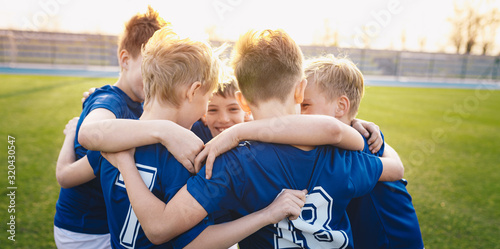 Happy kids in elementary school sports team celebrating soccer succes in tournament final game. Children soccer team team gathering together in a circle, to strategize, motivate and celebrate © matimix
