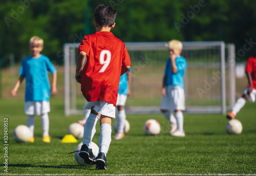 Children Training Soccer on Field. Young Kids Boys kicking Soccer Football Balls on Grass Pitch. Kids in Sportswear Practice Soccer Skills