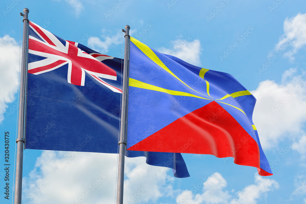 Reunion and Anguilla flags waving in the wind against white cloudy blue sky together. Diplomacy concept, international relations. Reunion and Anguilla flags waving in the wind against white cloudy blue sky together. Diplomacy concept, international relations.