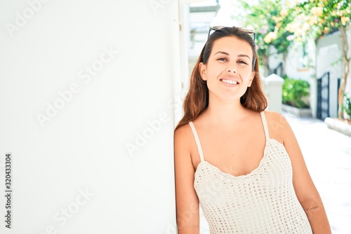 Young beautiful woman at the colorful village of Puerto de Mogan, smiling happy at the street leaning on white wall on summer holidays Free Download Young beautiful woman at the colorful village of Puerto de Mogan, smiling happy at the street leaning on white wall on summer holidays - GFXLoad
