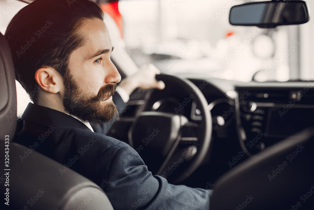 Man buying the car. Businessman in a car salon. Guy in a black suit Man buying the car. Businessman in a car salon. Guy in a black suit