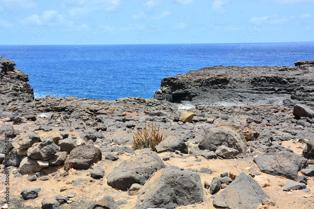 Basalt rocks, stones and turquoise, blue water in an ocean on Sal Island In Cape Verde