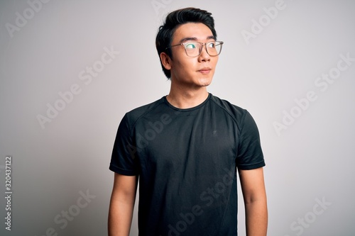 Photography Young handsome chinese man wearing black t-shirt and glasses over white background smiling looking to the side and staring away thinking