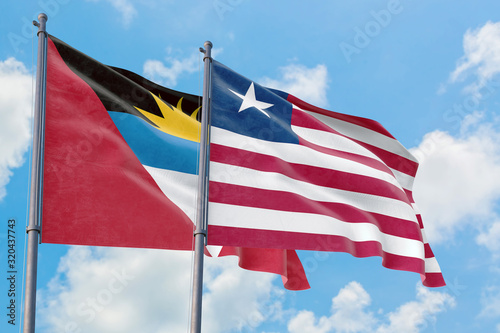 Liberia and Antigua and Barbuda flags waving in the wind against white cloudy blue sky together. Diplomacy concept  international relations.