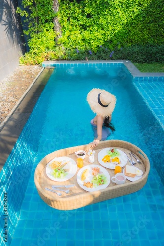 Portrait young asian woman happy smile enjoy with floating breakfast tray in swimming pool in hotel © siraphol
