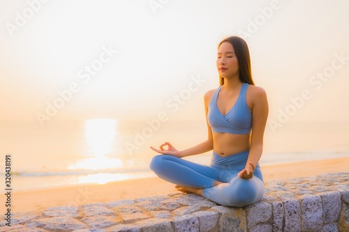 Portrait young asian woman do meditation around sea beach ocean at sunrise