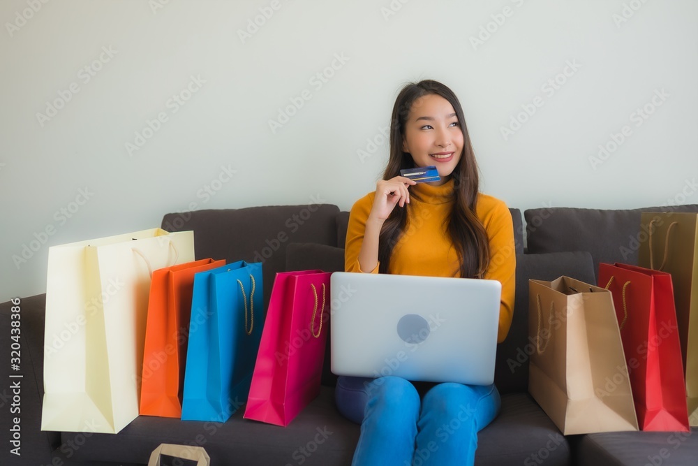 Portrait young asian woman using laptop computer with smart mobile phone and credit card for online shopping Portrait young asian woman using laptop computer with smart mobile phone and credit card for online shopping