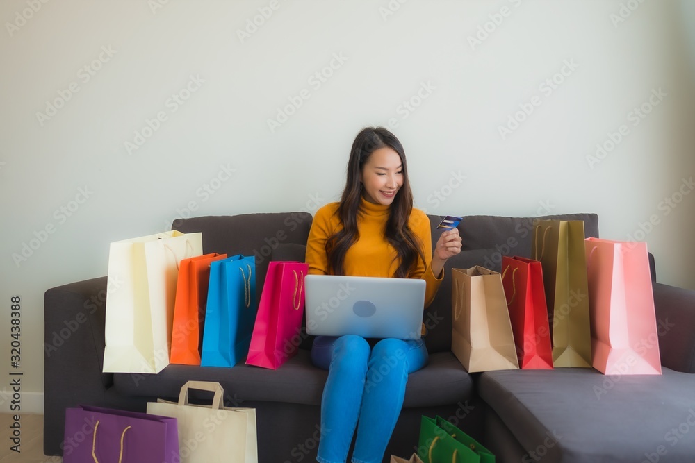 Portrait young asian woman using laptop computer with smart mobile phone and credit card for online shopping Portrait young asian woman using laptop computer with smart mobile phone and credit card for online shopping