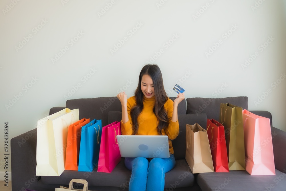 Portrait young asian woman using laptop computer with smart mobile phone and credit card for online shopping Portrait young asian woman using laptop computer with smart mobile phone and credit card for online shopping