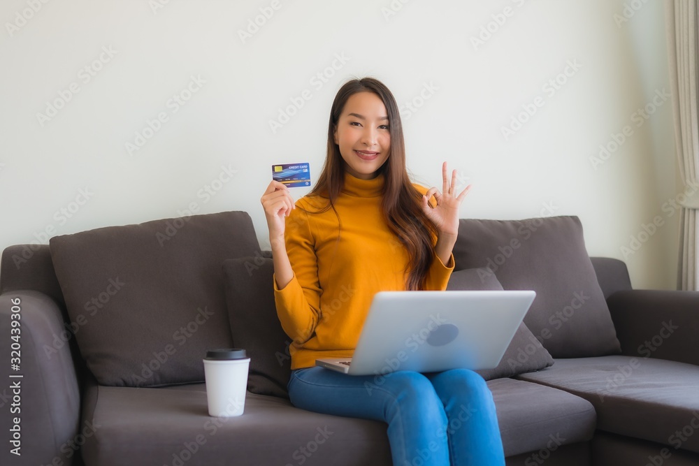 Portrait young asian woman using laptop computer with smart mobile phone and credit card for online shopping