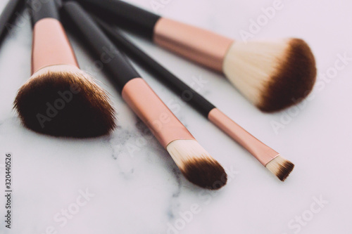 close-up of group of make-up brushes for face and eyes on marble tabletop at shallow depth of field