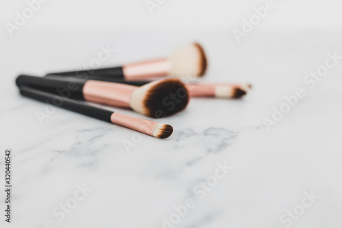 group of make-up brushes for face and eyes on marble tabletop at shallow depth of field