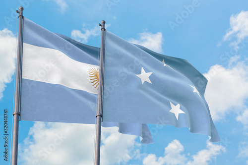 Micronesia and Argentina flags waving in the wind against white cloudy blue sky together. Diplomacy concept, international relations.