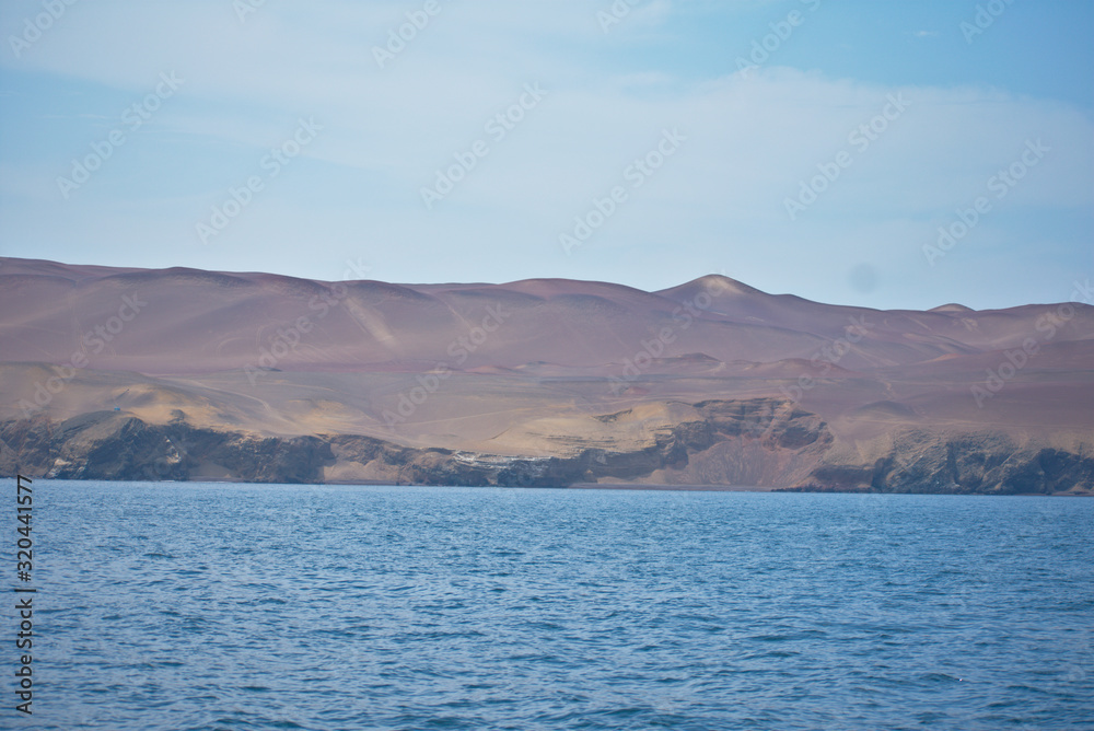 Ocean landscape sunny with a sandy mountain in the background in Paracas Peru