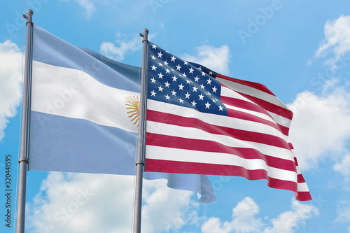 United States and Argentina flags waving in the wind against white cloudy blue sky together. Diplomacy concept  international relations.