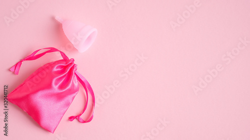 Menstrual cup and case on pink background with copy space. Eco-friendly reusable alternative to tampons and sanitary pads. Critical days, menstruation cycle, female healthcare concept