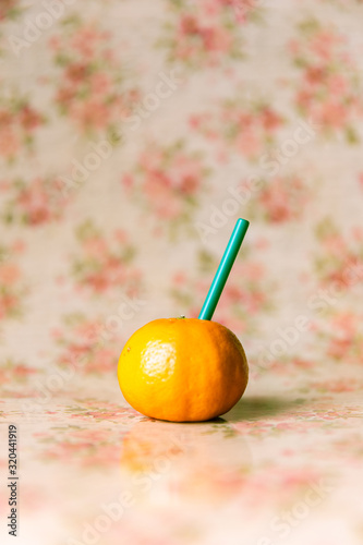 orange Mandarine mit Strohhalm aus Plastik um die Frische zu trinken