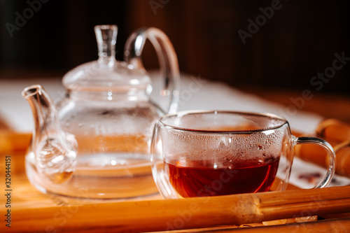 Cup of hot tea with rock sugar, dry leaves served in thermo glass cup