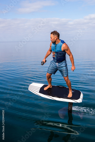 Obraz na płótnie Man riding an electric hydrofoil foil board on a lake with a life jacket w salonie