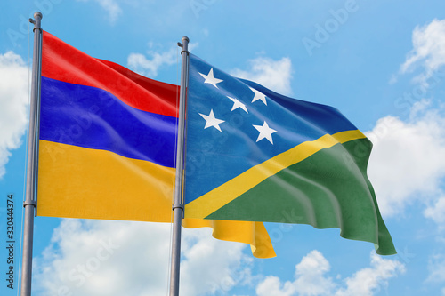 Solomon Islands and Armenia flags waving in the wind against white cloudy blue sky together. Diplomacy concept, international relations.