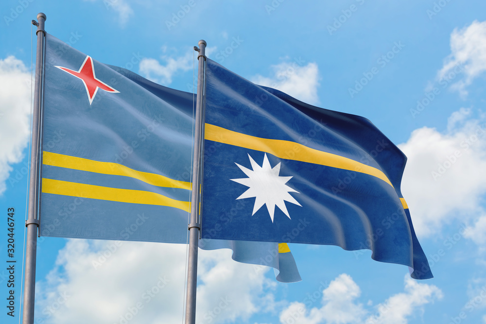Nauru and Aruba flags waving in the wind against white cloudy blue sky together. Diplomacy concept, international relations.