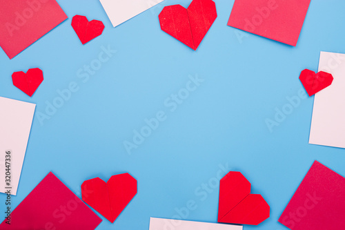 The red paper heart shapes and envelope over the blue background. Greeting cards, Love and Valentines day concept. Flat lay, top view, copy space.