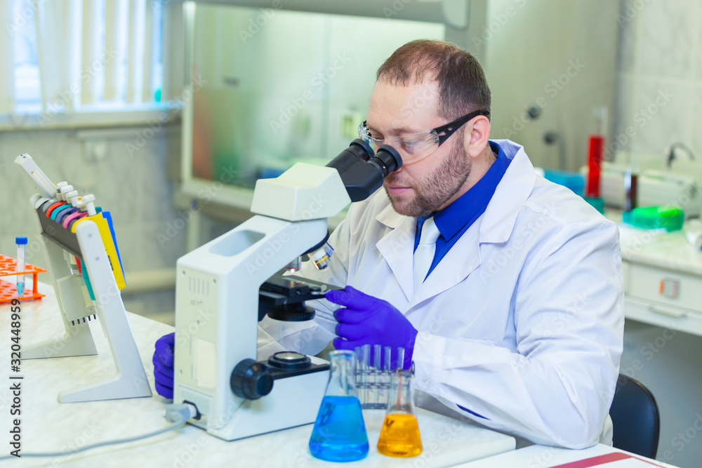 Specialist looking through microscope performing scientific research in a laboratory. Urine test. Specialist looking through microscope performing scientific research in a laboratory. Urine test.