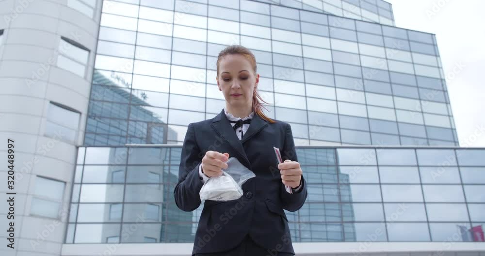 Caucasian business dressed woman is opening protective face mask, respirator. She is standing near business , financial building, wide shot. Virus protection concept, 4K. Caucasian business dressed woman is opening protective face mask, respirator. She is standing near business , financial building, wide shot. Virus protection concept, 4K.