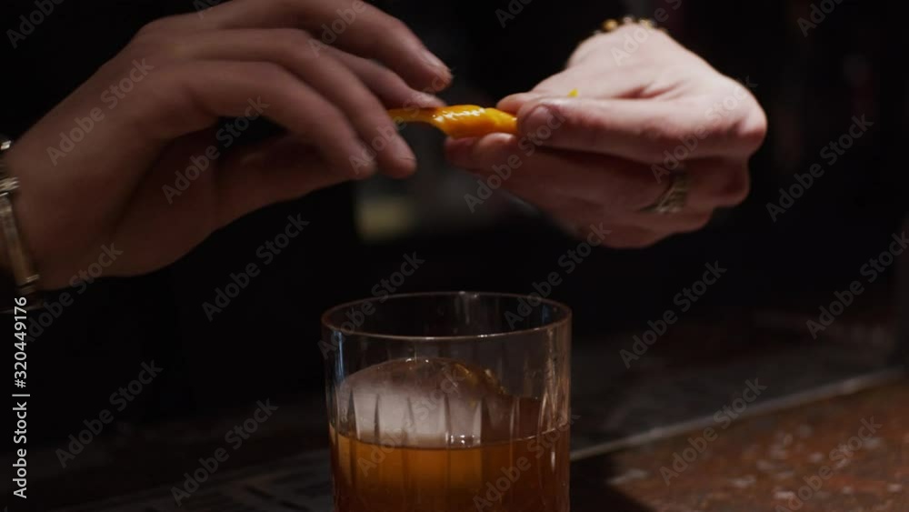 Process of making alcohol cocktail, decorating with orange peel, slow motion, shallow depth of field Process of making alcohol cocktail, decorating with orange peel, slow motion, shallow depth of field