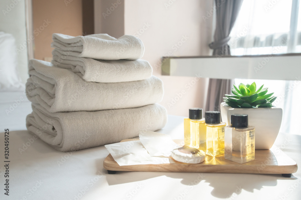 Set of hotel amenities (such as towels, shampoo, soap etc) on the bed. Hotel  amenities is something of a premium nature provided in addition to the room  when renting a room. Stock