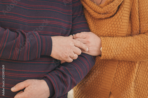 light-skinned heterosexual couple in knitted clothes without people holding hands tightly, close-up
