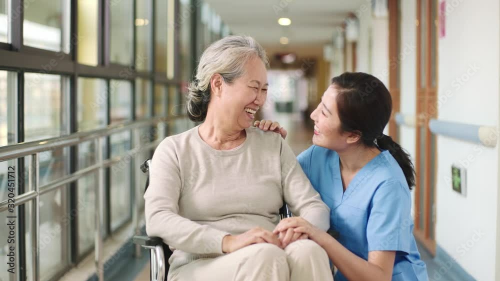 friendly staff of nursing home talking chatting with senior asian woman in hallway