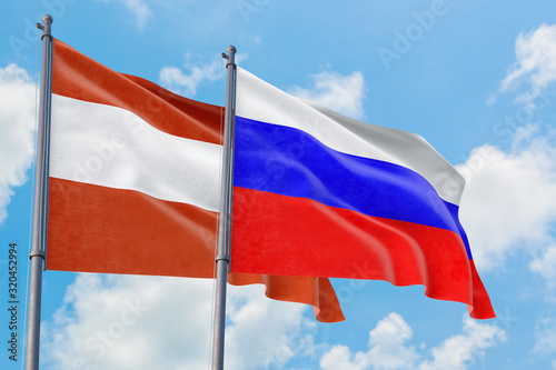 Photography Russia and Austria flags waving in the wind against white cloudy blue sky together
