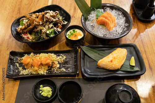 Salmon meal on table; salmon steak, sashimi, maki, steam egg and salad with crispy skin salmon. Healthy food with rich in omega-3 meal.