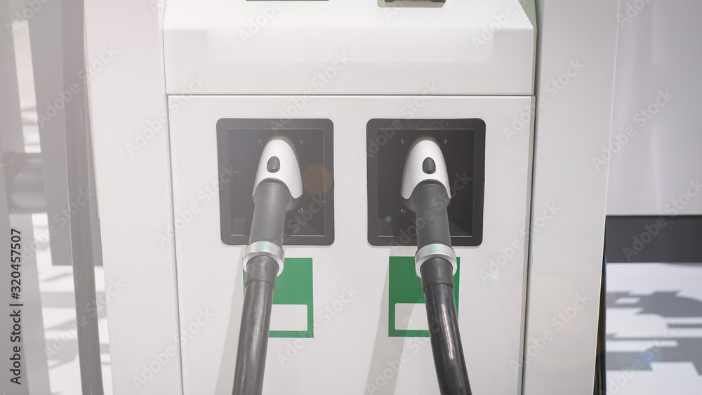 Electric car or ev is charging at station . man use white power cable and plug on nature background. eco and clean energy concept with the mobile phone smart technology. zero gas and no transmission. Electric car or ev is charging at station . man use white power cable and plug on nature background. eco and clean energy concept with the mobile phone smart technology. zero gas and no transmission.