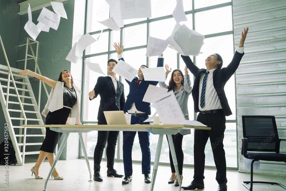 Fototapeta premium business people excited happy smile,Group of confident business people throwing paper in air while working behind the glass wall,Success team concept.