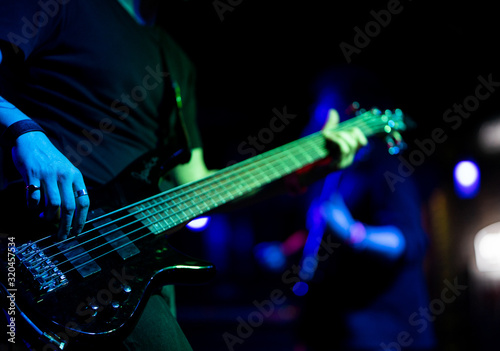A man plays a guitar on a dark stage at a rock concert
