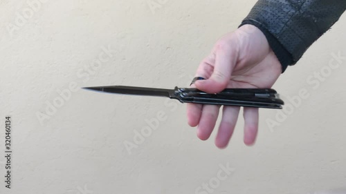 hand making tricks with butterfly knife on light background, butterfly knife opening and closing, outlaw handles knife outdoors. thief playing with stabbing weapon. gangster using weapon. video 4k photo